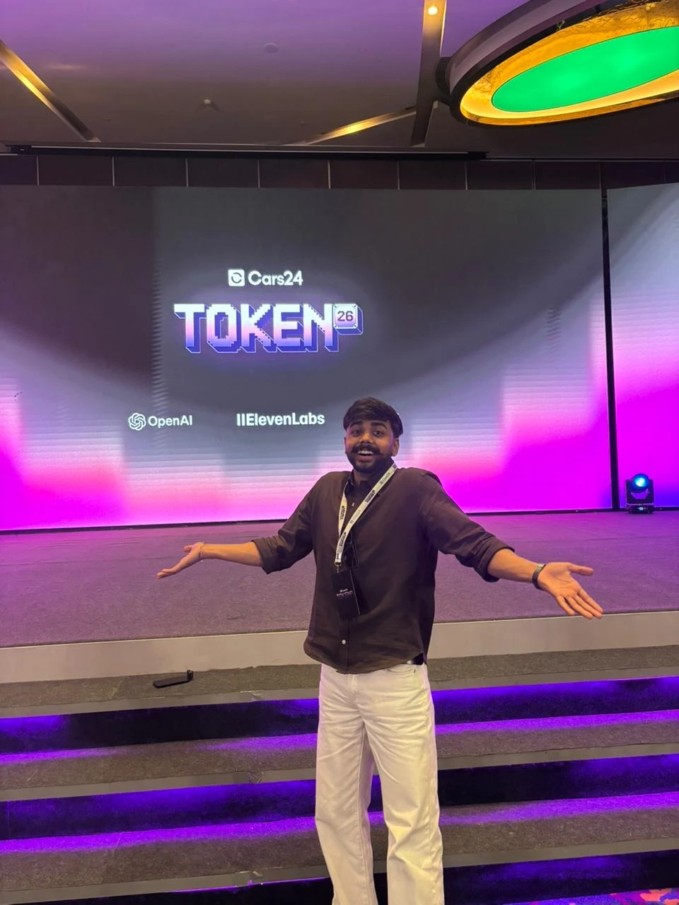 Nishant on the Token '26 stage at Cars24's AI hackathon, with the Cars24, OpenAI and ElevenLabs logos on the screen behind him